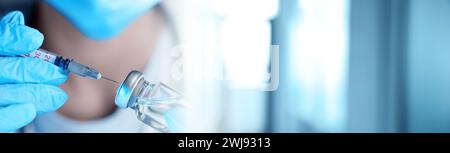 Arzt füllt Spritze mit Medikamenten aus Glasfläschchen auf verschwommenem Hintergrund, Großaufnahme. Bannerdesign Stockfoto