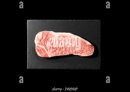 Frisches rohes Rindersteak auf einem Steinteller vor schwarzem Hintergrund. Wagyu-Rindersteak. Blick von oben. Stockfoto