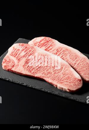 Frisches rohes Rindersteak auf einem Steinteller vor schwarzem Hintergrund. Wagyu-Rindersteak. Stockfoto
