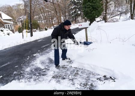 Chappaqua, New York - 13. Februar 2024 - Ein Mann schaufelt seine Auffahrt, nachdem ein Wintersturm über einen Fuß schweren nassen Schnee auf dem Westchester County New Yo abgefeuert hatte Stockfoto