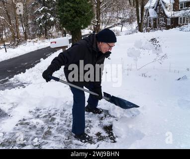 Chappaqua, New York - 13. Februar 2024 - Ein Mann schaufelt seine Auffahrt, nachdem ein Wintersturm über einen Fuß schweren nassen Schnee auf dem Westchester County New Yo abgefeuert hatte Stockfoto