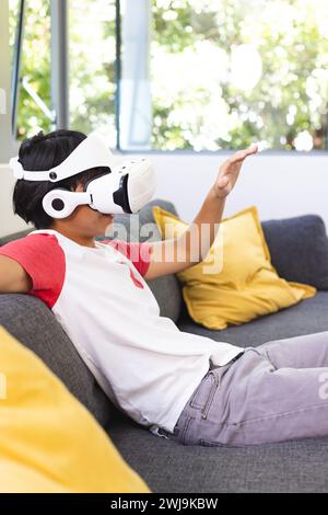 Der Teenager Asian Boy erkundet die virtuelle Realität von einer Couch zu Hause aus Stockfoto