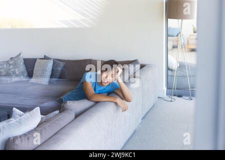 Teenager asiatischer Junge, der sich zu Hause auf einer Couch entspannt, mit Kopierraum Stockfoto