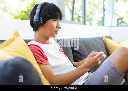 Teenager asiatischer Junge spielt gern zu Hause, konzentriert und engagiert Stockfoto