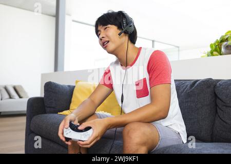 Teenager asiatischer Junge spielt gerne in einer häuslichen Umgebung Stockfoto