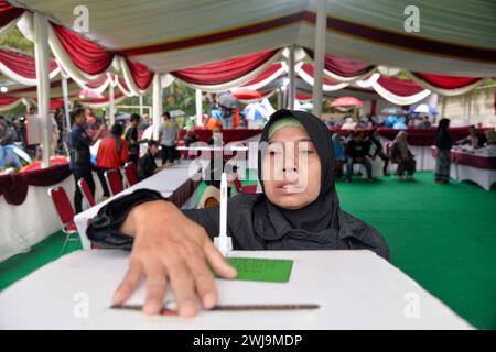 Bogor, Indonesien. Februar 2024. Eine Wählerin gibt ihre Stimme am 14. Februar 2024 in Bogor, Indonesien, am Wahllokal Nr. 35 ab. Die Wahl für die Parlamentswahlen in Indonesien begann offiziell am Mittwochmorgen, so die Allgemeine Wahlkommission (KPU) des Landes. Quelle: Xu Qin/Xinhua/Alamy Live News Stockfoto