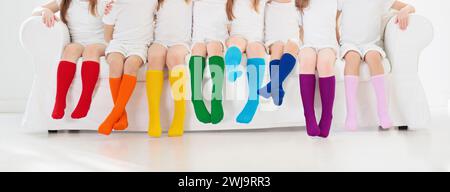 Kinder tragen bunte Regenbogensocken. Schuhkollektion für Kinder. Verschiedene knielange Stricksocken und Strumpfhosen. Kinderkleidung und -Bekleidung. Stockfoto