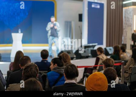 Das Publikum hört einem verschwommenen Referenten aufmerksam zu, der auf einer Geschäftskonferenz mit modernem Ambiente spricht. Stockfoto