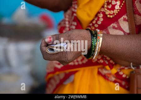 Eine alte indische Frau in einem Saree, die Rupie in indischer Währung hält. Nahaufnahme der Hände indischer Frauen, die Geld halten. Reisefoto, Straßenfoto Stockfoto