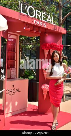 L'Oréal Markenaktion zum valentinstag 2024 im Zentrum von Bangkok, Thailand, Südostasien posiert eine junge Frau mit Blumen vor einem Stand Stockfoto