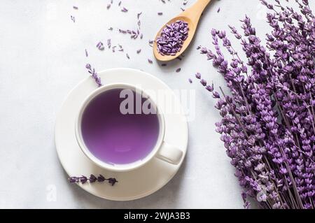 Tasse Lavendeltee mit getrockneten Lavendelblüten auf rustikalem Tisch, Kräuter-entspannender Tee. Lavendula oleum Stockfoto