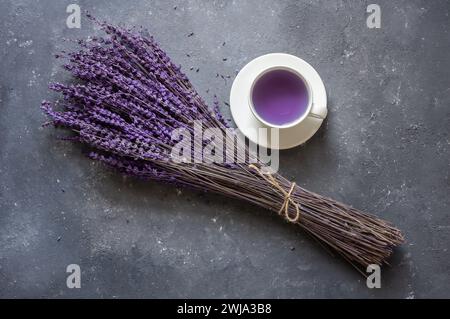 Tasse Lavendeltee mit getrockneten Lavendelblüten auf rustikalem Tisch, Kräuter-entspannender Tee. Lavendula oleum Stockfoto