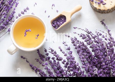 Tasse Lavendeltee mit getrockneten Lavendelblüten auf rustikalem Tisch, Kräuter-entspannender Tee. Lavendula oleum Stockfoto