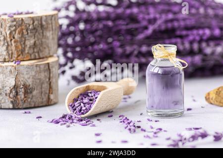 Glasflasche ätherisches Lavendelöl mit getrockneten Lavendelblüten und Samen auf weißem Tisch, Aromatherapie-Spa-Massagekonzept. Lavendula oleum Stockfoto