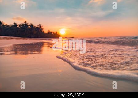 Fantastischer Blick aus der Nähe auf die ruhigen Meerwasserwellen mit orangefarbenem Sonnenaufgang Sonnenuntergang. Tropische Inselstrandlandschaft, exotische Küste. Sommerurlaub Stockfoto
