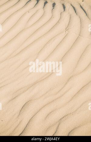 Nahaufnahme natürlicher Sandmuster, die weiche, wellenartige Texturen am Strand erzeugen, mit einer ruhigen und einfachen Ästhetik Stockfoto