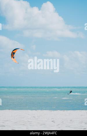 Ein Kitesurfer gleitet über das türkisfarbene Wasser von Miami Beach, Florida, mit einem farbenfrohen Drachen, der am sonnigen Himmel aufsteigt. Stockfoto