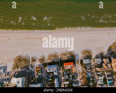 Ein Luftbild fängt den ruhigen Strand in Miami, Florida, ein, umgeben von grünem Grün und einer friedlichen Küste, wenn der Abend sich nähert. Stockfoto