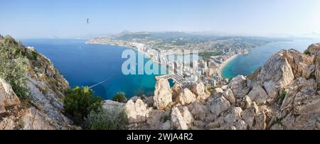 Spektakuläre Aussicht auf die Stadt mitten im blauen Wasser und felsigen Formationen bei Sonnenaufgang in Penon de Ifach in Calpe, Alicante, Spanien Stockfoto