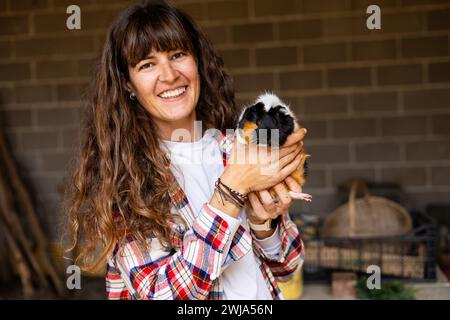 Porträt einer glücklichen jungen Farmerin mit einem niedlichen Meerschweinchen. Tierschutz und Pflege auf einem Bio-Bauernhof. Stockfoto