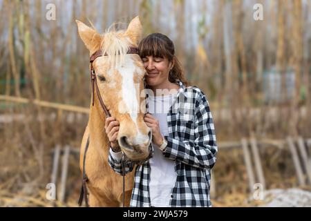 Eine junge Reiterin umarmt ihr braunes Pferd in einem Reitzentrum Stockfoto