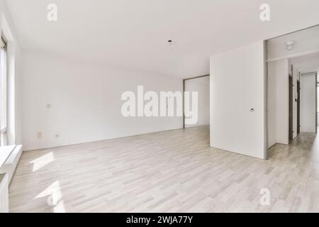 Ein heller und luftiger, leerer Raum mit hellem Holzlaminatboden und weißen Wänden, mit Sonnenlicht Stockfoto
