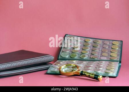 Die Сoins sind in transparenten Blasen auf rosa Hintergrund angeordnet. Seite aus Album voll mit alten Münzen. Die Lupe wird auf Blasen gelegt. Coin stora Stockfoto