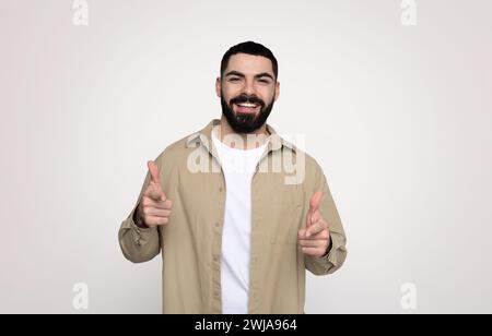 Ein glücklicher, selbstbewusster, gutaussehender junger lateinmann mit einem Bart in gelegentlichen Zeigefingern vor der Kamera Stockfoto
