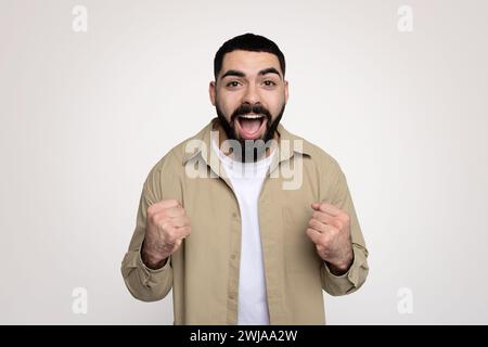 Glücklicher schockierter junger latin-Mann-Sieger mit Bart in lässiger Freizeit mit offenem Mund Stockfoto