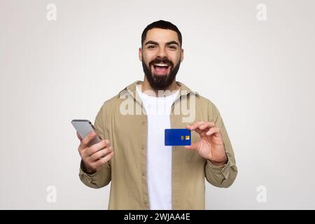 Fröhlich schockiert, hübscher junger lateinamerikanischer Shopaholic mit Bart in zwangloser Weise mit offenem Mund Stockfoto