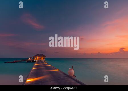 Fantastische Landschaft bei Sonnenuntergang. Malerischer Sommeruntergang auf den Malediven. Luxuriöse Resort-Villen am Meer mit sanften LED-Lichtern unter farbenfrohem Himmel. Traumhafter Sonnenuntergang Stockfoto
