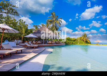 Wunderschöner Luxusschirm und Sessel um den Außenpool im Hotel und Resort mit Kokospalmen am blauen Himmel. Luxuriöser Sommerurlaub Stockfoto