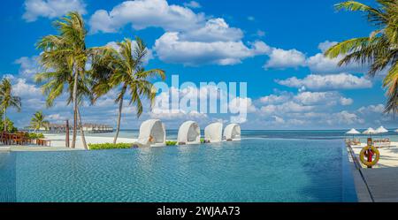 Wunderschöner Luxusschirm und Sessel um den Außenpool im Hotel und Resort mit Kokospalmen am blauen Himmel. Luxuriöser Sommerurlaub Stockfoto