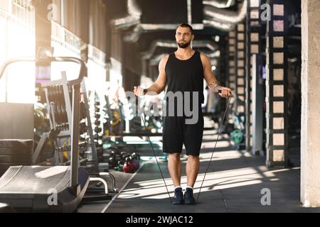 Cardio-Workout. Selbstbewusster muskulöser Mann, der mit Seilspringen im Fitnessraum springt Stockfoto