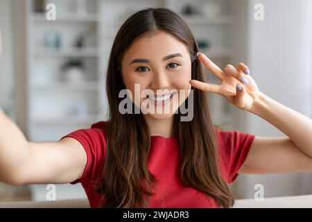 Positive Junge Asiatische Frau, Die Selfie Nimmt, Während Sie Sich Zu Hause Entspannt Stockfoto