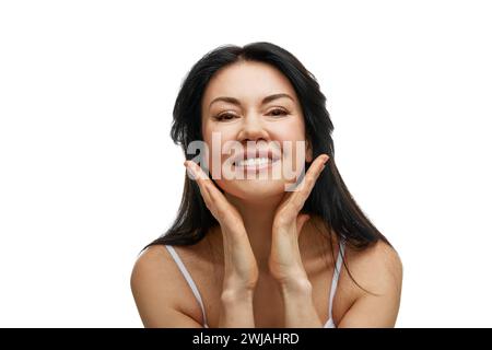 Porträt einer fröhlichen Frau mit Händen, die das Kinn berühren und die Kamera vor weißem Studiohintergrund betrachten. Stockfoto