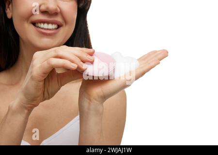 Nahporträt einer Frau mit rosa Gesichtsreinigungsbürste mit Schaum vor weißem Atelierhintergrund. Stockfoto