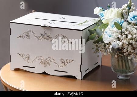 Weiße hölzerne Hochzeitsdose für Karten, Geld, Geschenke für Jungvermählte auf dem Tisch. Hochzeitsaccessoires. Spendenbox Stockfoto