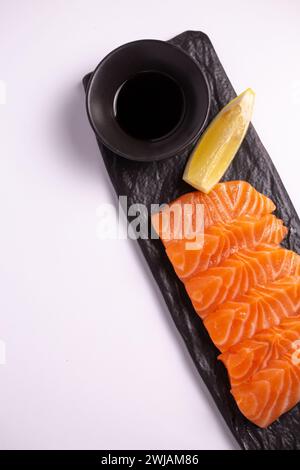 Lachsfilet mit Zitronen- und Sojasauce auf schwarzem Steinteller, Nahaufnahme von oben. Stockfoto