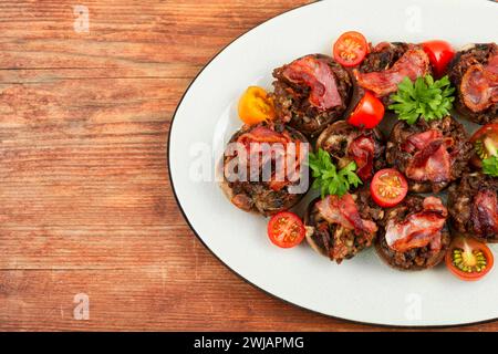 Gebratene Champignonpilze mit Fleisch und Tomaten auf ländlichem Holzhintergrund. Draufsicht. Kopierbereich. Stockfoto