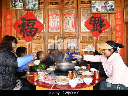 Peking, chinesische Provinz Yunnan. Februar 2024. Eine einheimische Familie genießt ihr Abendessen im Dorf Wenping im Bezirk Jianchuan in der Autonomen Präfektur Dali Bai, südwestchinesische Provinz Yunnan, 13. Februar 2024. Die Menschen im ganzen Land tauchten in die festliche Atmosphäre des chinesischen Neujahrs ein, indem sie traditionelle Speisen und lokale Snacks genossen. Quelle: Zhao Qingzu/Xinhua/Alamy Live News Stockfoto