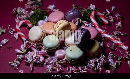 Farbenfrohe Macarons und Zuckerstangen umgeben von Blüten. Stockfoto