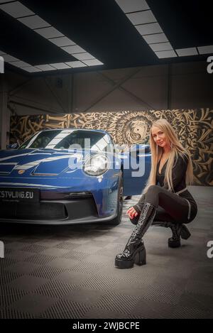 Porsche 911 GT3 mit modischer Frau in künstlerischem Indoor-Setting Stockfoto