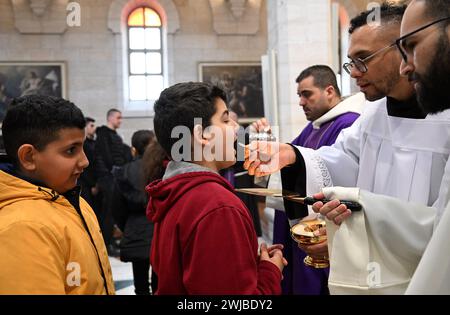 Bethlehem, Westjordanland. Februar 2024. Ein palästinensischer katholischer Junge empfängt die heilige Kommunion während der Aschermittwochs-Messe, dem ersten Fastentag in St. Katharinenkirche in Bethlehem, Westjordanland, am Mittwoch, 14. Februar 2024. Aschenmittwoch markiert den Countdown bis Ostern mit Gebet, Fasten und Verehrung Gottes. Foto: Debbie Hill/ Credit: UPI/Alamy Live News Stockfoto