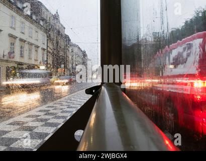 Straßenszene im Regen durch das Glas einer Bushaltestelle - Prag Stockfoto