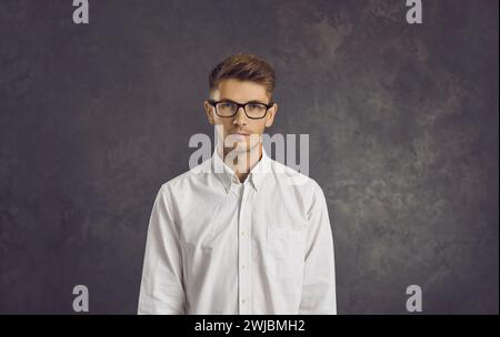 Studio-Porträt eines ernsthaften jungen Geschäftsmannes oder Programmierers, der auf grauem Hintergrund steht. Stockfoto