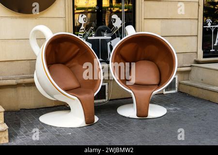 Zwei weiße Tassen Kaffee in Form eines Sessels auf der Straße in der Nähe des Cafés. Stockfoto