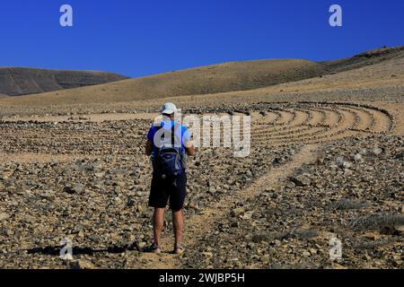 Mann besucht Wolf Pattons Labyrinth - niedriges Steinlabyrinth mitten im Nirgendwo in der Nähe von El Cotillo, Fuerteventura. Vom November 2023 Stockfoto