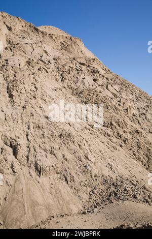 Hügel aus feinem, leicht braunem Sand vor blauem Himmel auf der Baustelle. Stockfoto