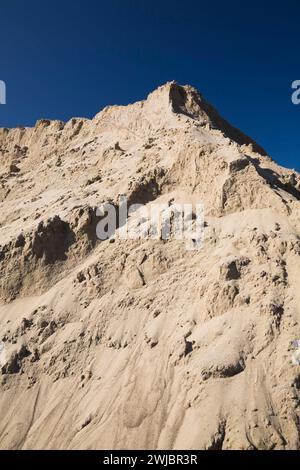 Hügel aus feinem hellbraunem Sand gegen blauem Himmel auf der Baustelle. Stockfoto